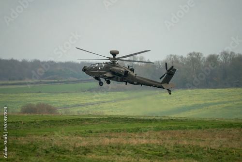 British army AH-64E Boeing Apache Attack helicopter (ZM722 ArmyAir606) in a controlled hover over grass meadow, Wiltshire UK 