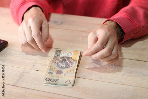 counting polish zloty banknotes with calculator on table