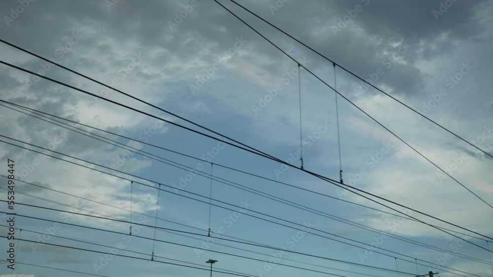 Electric wires passing by on moving train. Sky view POV from passenger perspective traveling on railroad transportation. Daydreaming concept Electric wires passing by on moving train. Sky view POV from passenger perspective traveling on railroad transportation. Daydreaming concept