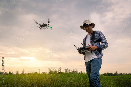Agricultural specialist controls agriculture drone with remote controller for spraying fertilizer and pesticide at rice field. Agriculture 5g, Smart farming, Smart technology concept. © Satawat