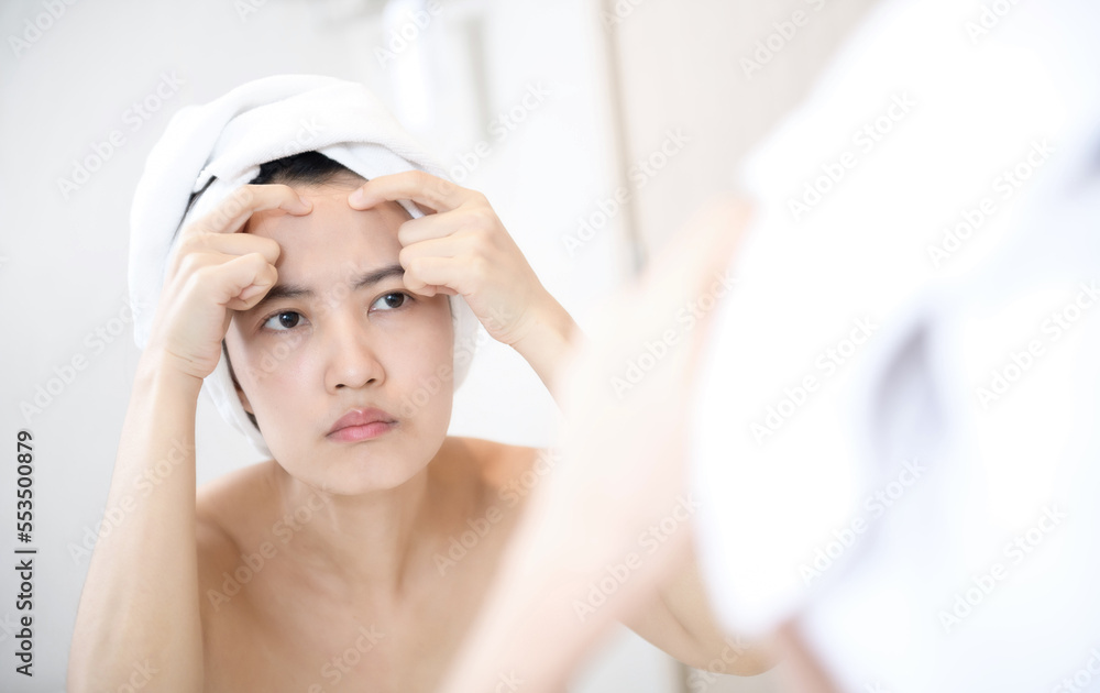 Problem skin. Concerned young asian women popping pimple on cheek while standing near mirror in bathroom. young asian women with acne Problem skin. Concerned young asian women popping pimple on cheek while standing near mirror in bathroom. young asian women with acne