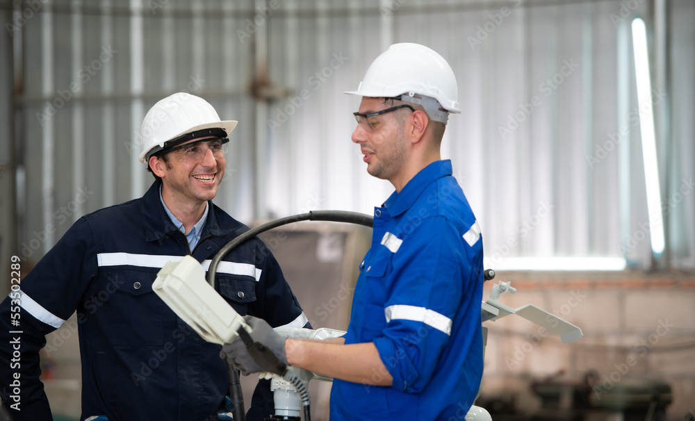 The two engineers check the operation of welding robots. ready to transfer and exchange experiences each other's skills The two engineers check the operation of welding robots. ready to transfer and exchange experiences each other's skills