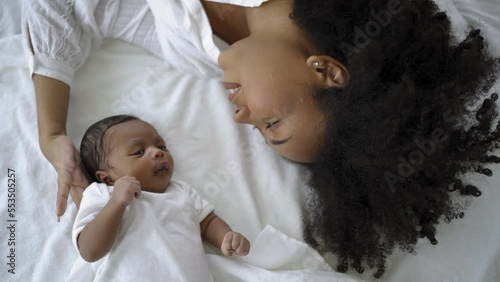 Closeup portrait of beautiful young African American mother day girl kiss healthy newborn baby sleep in bed flat lay copy space. Healthcare medical love black woman lifestyle mother's day, top view