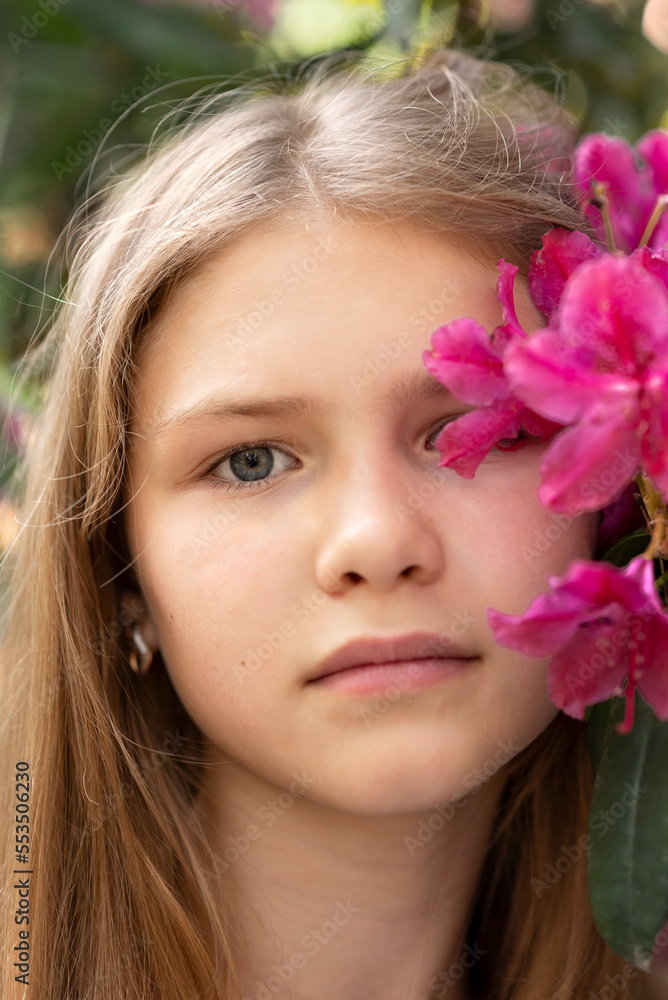 Portrait of young pretty teenage girl with flower near the face. Purple, viva magenta flowers blush in trendy 2023 color. Girl in a spring garden. Portrait of young pretty teenage girl with flower near the face. Purple, viva magenta flowers blush in trendy 2023 color. Girl in a spring garden.
