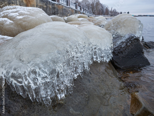 Transparent ice and ice icicles on stones on the shore of the Onega Lake in Karelia in autumn after frost photo