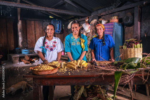 Retrato de mujeres indigenas viendo a camara en una cocina antigua con estufa de leña.