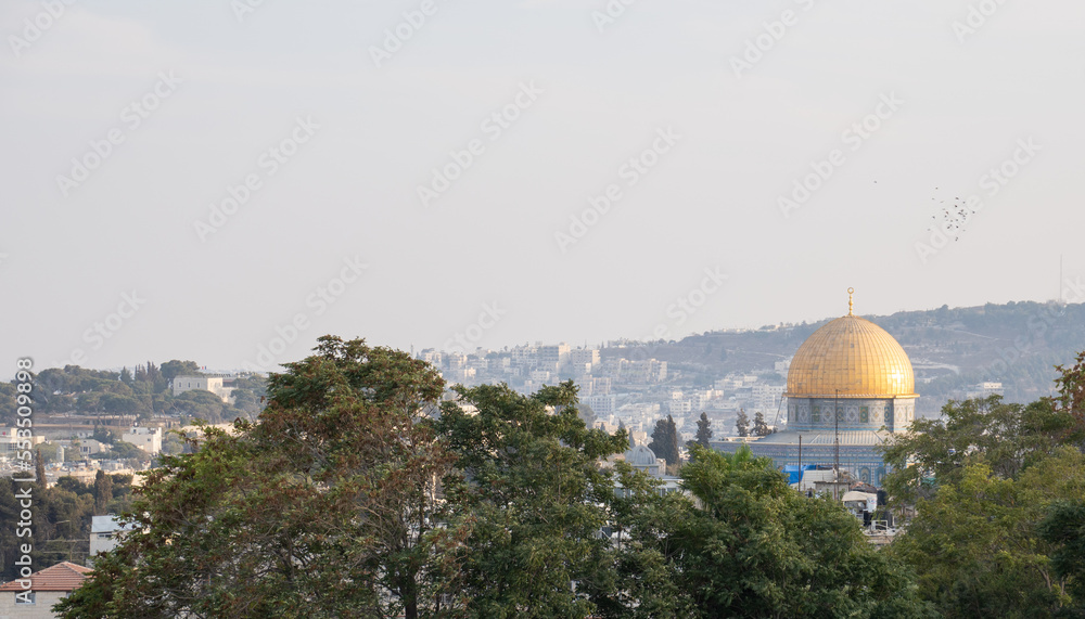 The beautiful golden Islamic dome of the Dome of the Rock with the hills of Jerusalem in the background