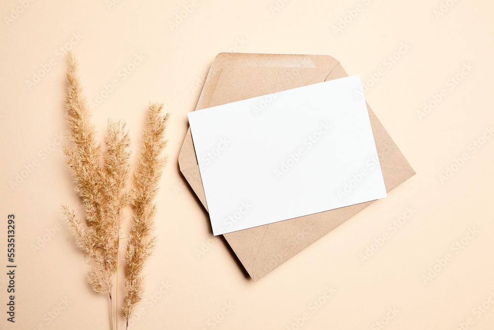 Holiday greeting card mockup with dry grass on beige background, top view, flat lay. White wedding invitation card Holiday greeting card mockup with dry grass on beige background, top view, flat lay. White wedding invitation card