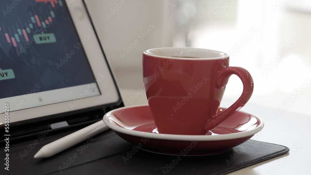 Red cup of coffee with stock investment on tablet board screen Red cup of coffee with stock investment on tablet board screen