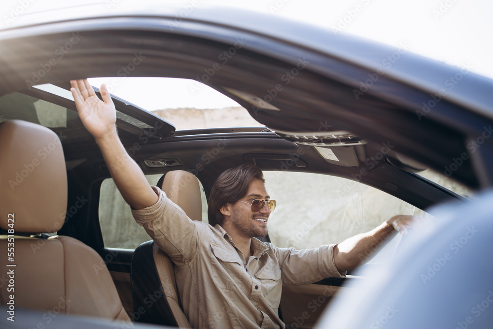 Handsome man driving his car in sand park