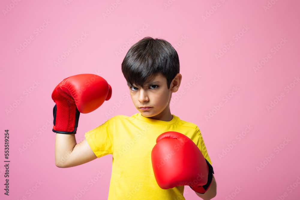 Boy with boxing gloves looking at camera and showing muscle Boy with boxing gloves looking at camera and showing muscle