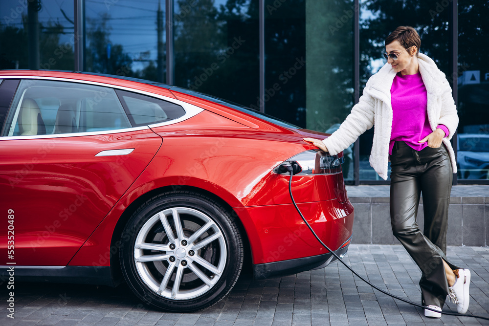 Woman charging electric car by the office building Woman charging electric car by the office building