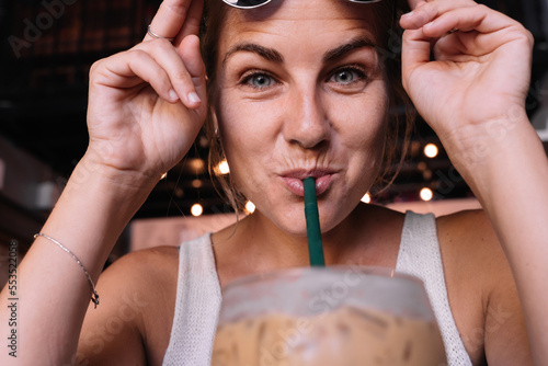 Close up portrait of a woman drinking iced coffee with a straw