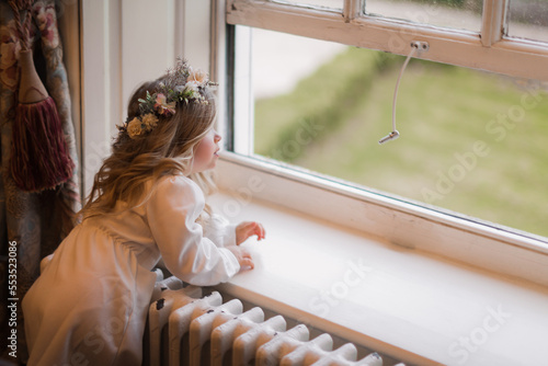 Canvas Print Little girl dressed up standing in diffused window light