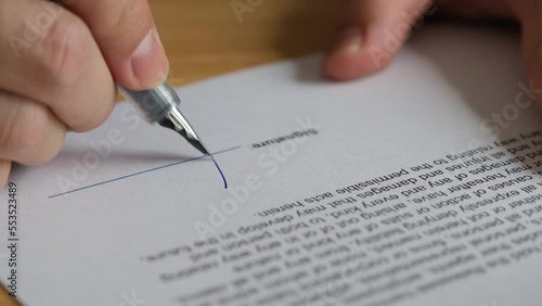 Man's hand is using a pen to sign a contract or consent form.