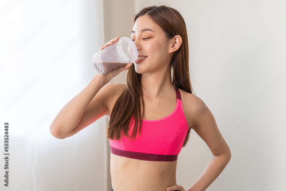 Young sporty woman drinking protein powder in a cup to make replacement food meal after workout Young sporty woman drinking protein powder in a cup to make replacement food meal after workout