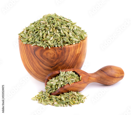 Fennel seeds in wooden bowl and spoon, isolated on white background. Green fennel grains. Spices and herbs.