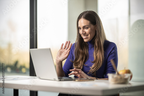 Young happy female worker in her office working on laptop