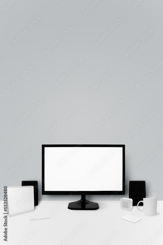 There is a monitor and office supplies on the desk in front of the wall. There is a monitor and office supplies on the desk in front of the wall.