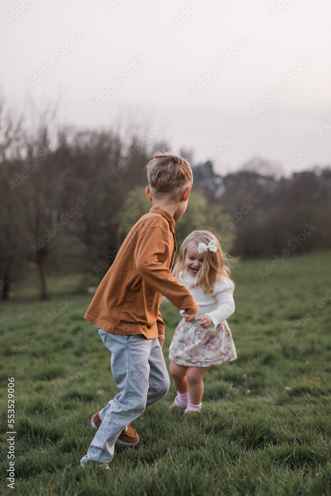 Brother and sister running together outdoors having fun, smiling and laughing Brother and sister running together outdoors having fun, smiling and laughing