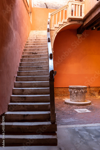 Venice, its characteristic architecture. The detail of an internal courtyard, with a well, overlooked by a magnificent staircase leading to the upper floor. photo