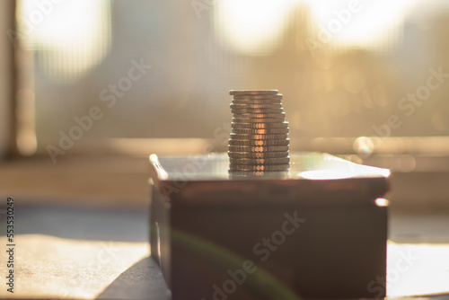 A column of metal coins on a smartphone on a bright sunny day. Close-up with a blurred background.