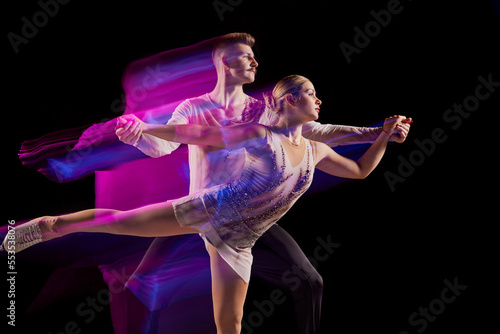Canvas Print Portrait of young man and woman, figure skating athletes dancing isolated over b