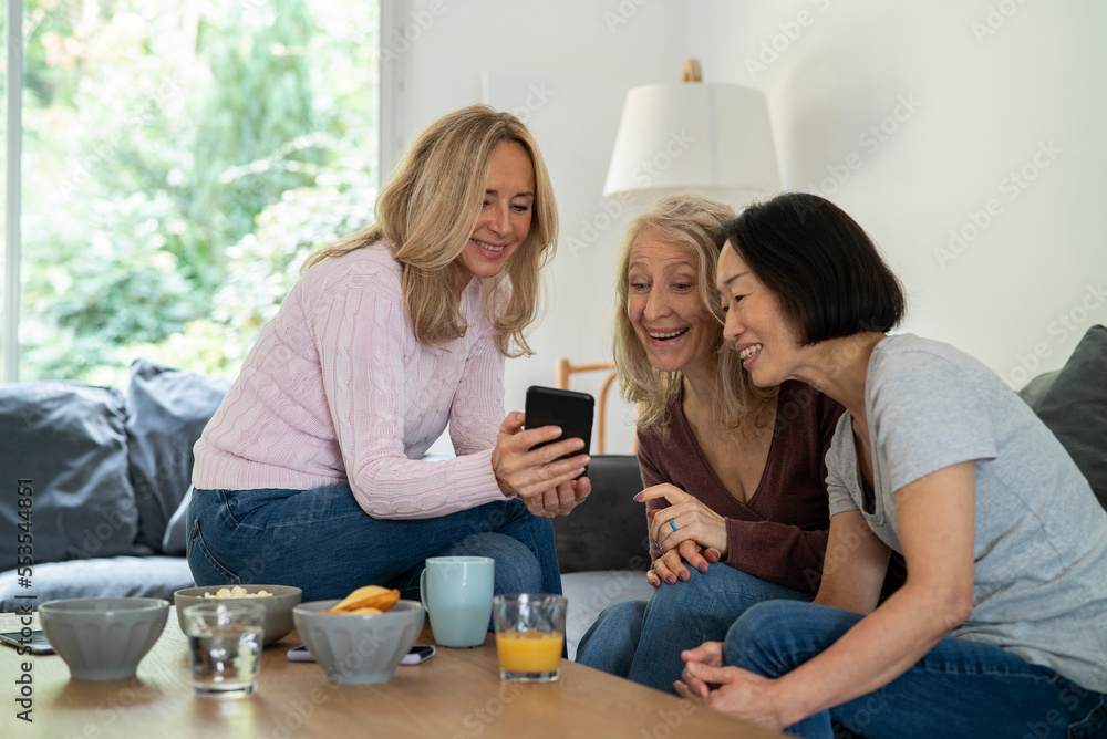 Senior women watching video on smart phone while sitting on sofa Senior women watching video on smart phone while sitting on sofa
