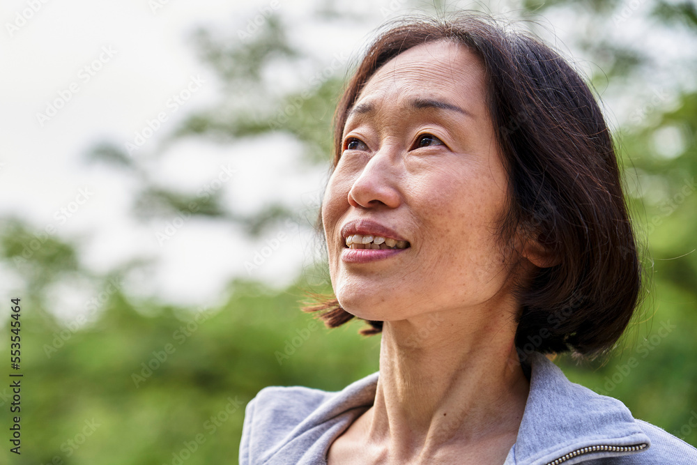 Senior Asian woman looking up while standing outdoors Senior Asian woman looking up while standing outdoors