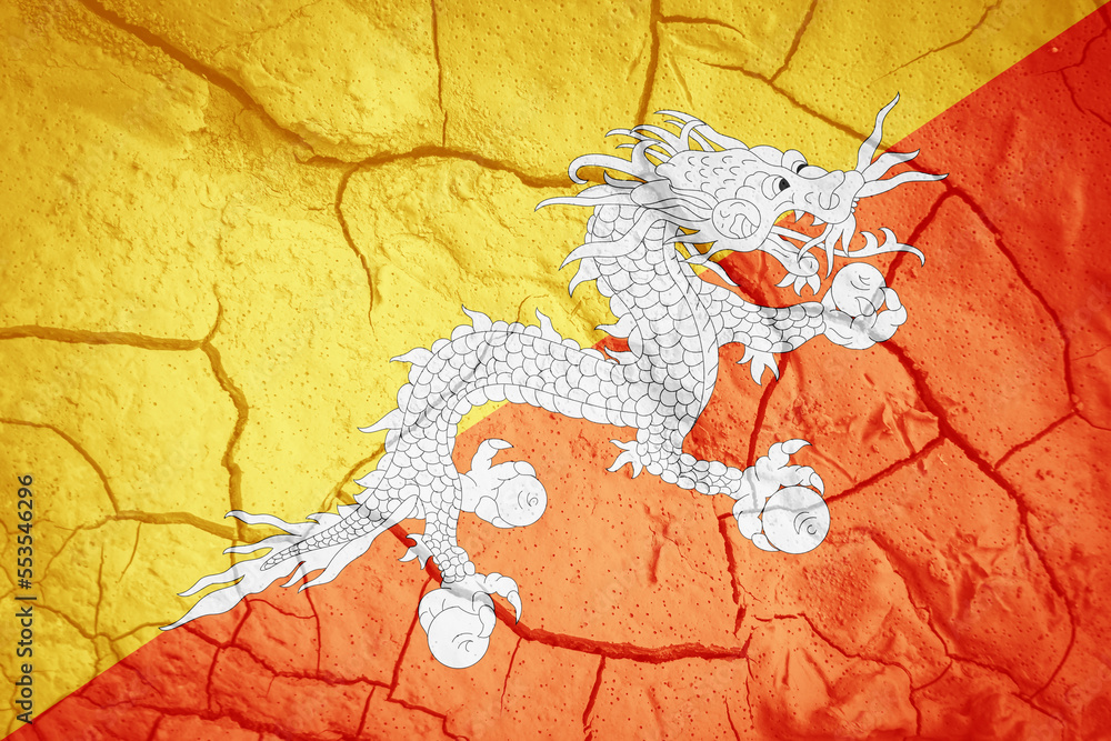 Naklejka premium Flag of Bhutan. Bhutanese symbol. Flag on the background of dry cracked earth. Bhutanese flag with drought concept