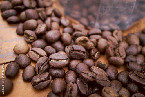 Roasted dark brown coffee beans on top of the wooden table, closeup coffee seeds background