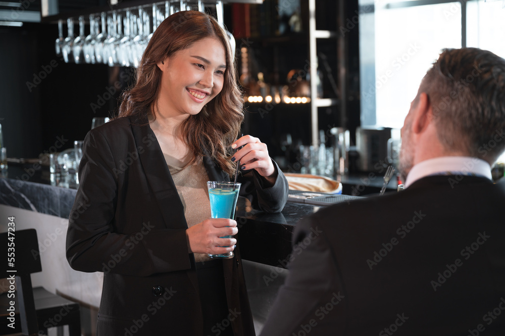 Asia Businesswoman with businessman drink cocktail at bar in hotel restaurant	