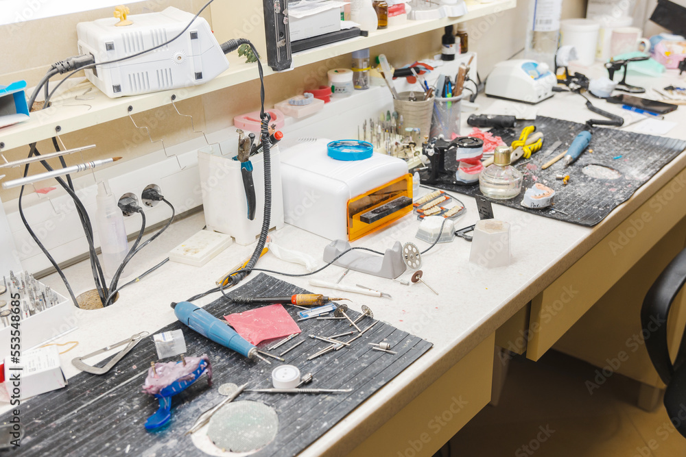 Photo of a dirty and full of tools desk where ceramic teeth are made in a dentistry office. Photo of a dirty and full of tools desk where ceramic teeth are made in a dentistry office.