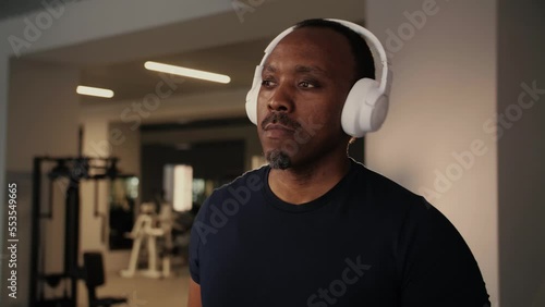 Serious Sports Black man with headphones walking on treadmill in gym.Fitness Young Man doing activity cardio training wear sportwear.Overweight Male doing workout and listen music.