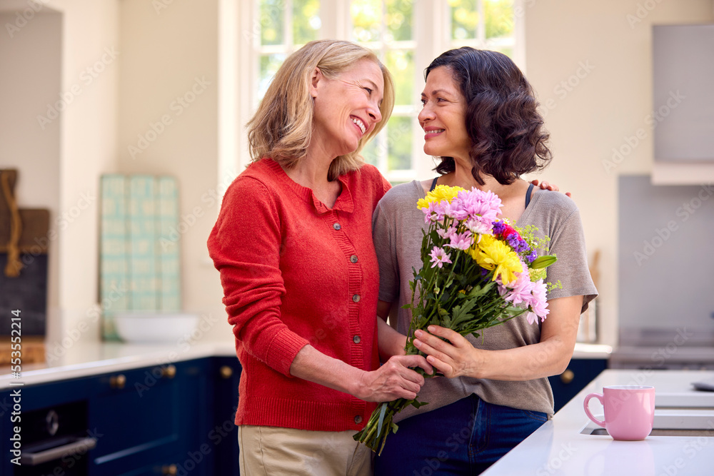 Zdjęcie Stock Loving Same Sex Mature Female Couple In Kitchen With Woman Giving Partner Flowers