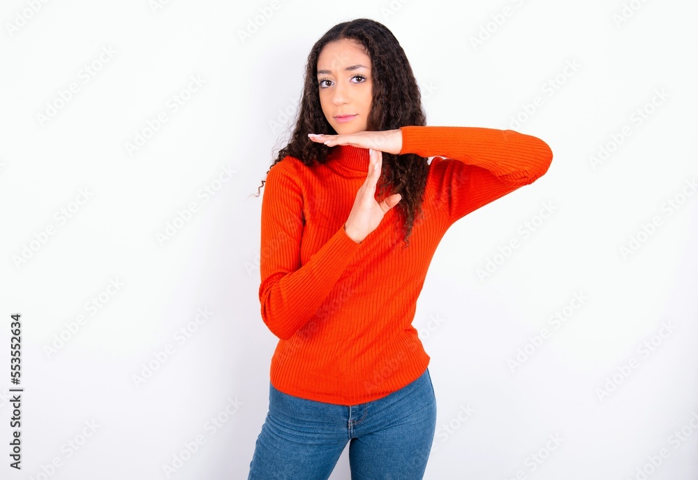 teen girl with curly hair wearing red sweater over white background feels tired and bored, making a timeout gesture, needs to stop because of work stress, time concept. teen girl with curly hair wearing red sweater over white background feels tired and bored, making a timeout gesture, needs to stop because of work stress, time concept.