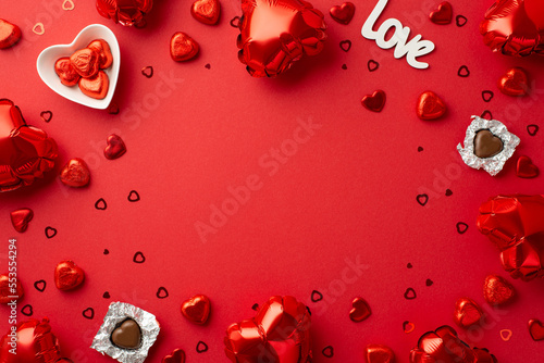 Valentine's Day concept. Top view photo of heart shaped balloons chocolate candies saucer inscription love and confetti on isolated red background with blank space in the middle