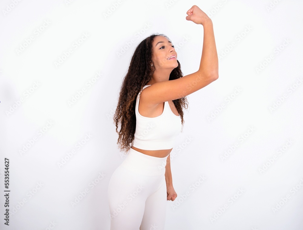 Profile photo of teen girl with curly hair wearing white sport set over white background supporting soccer team World Cup 2022 raise fist shouting