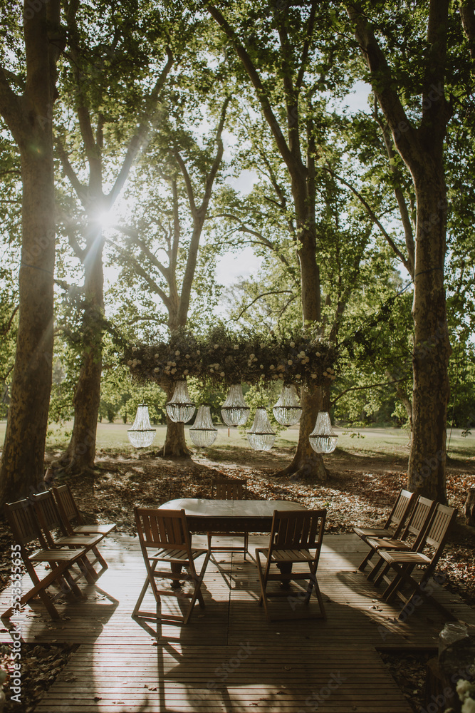 Decorated luxury wedding ceremony place in the garden. White empty chairs and arch decorated with plants.