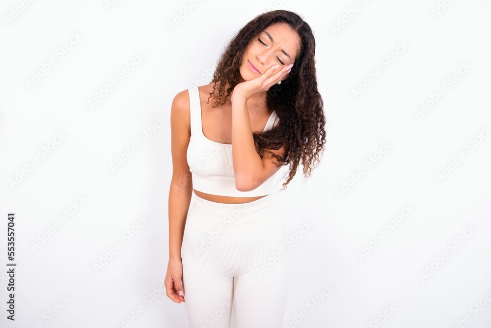teen girl with curly hair wearing white sport set over white background with toothache teen girl with curly hair wearing white sport set over white background with toothache