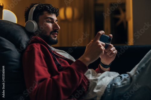 Side view of a man with headphones looking at his phone