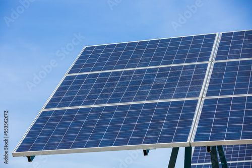 Solar cells panels. Solar farm on blue sky background. Photovoltaics solar cells panels in solar power station. Green energy from natural and Clean energy concept