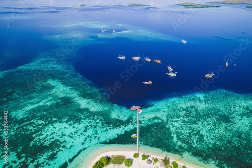 Aerial view of boats moored offshore of an island in Komodo National Park with a dock extending into the surrounding turquoise water; East Nusa Tenggara, Lesser Sunda Islands, Indonesia photo