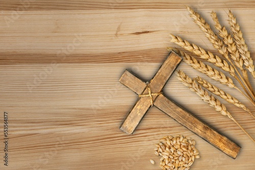 Wood cross and golden wheat on desk