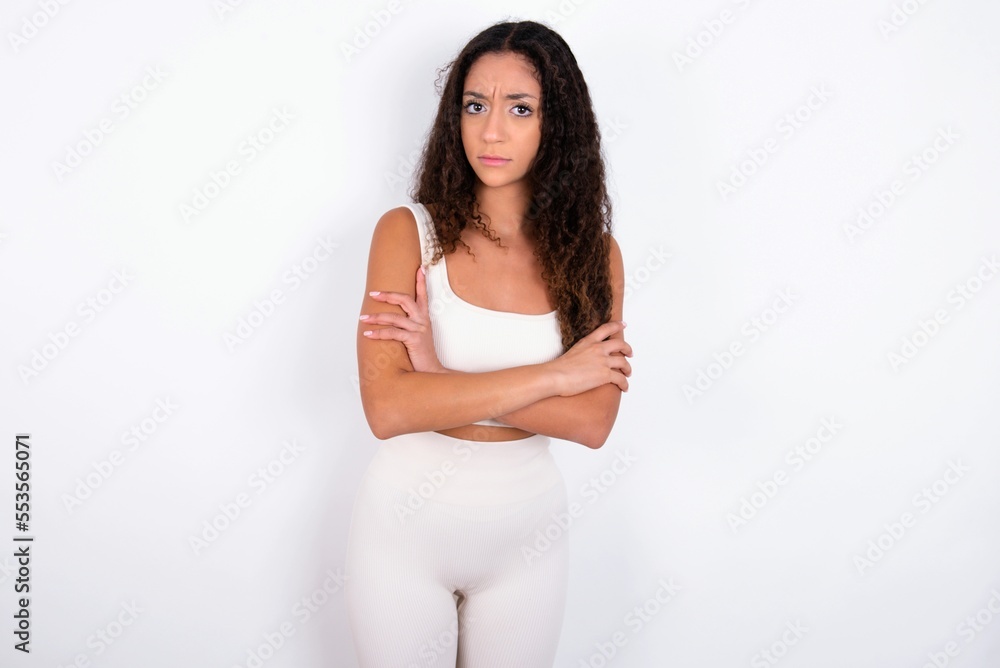 teen girl with curly hair wearing white sport set over white background Pointing down with fingers showing advertisement, surprised face and open mouth