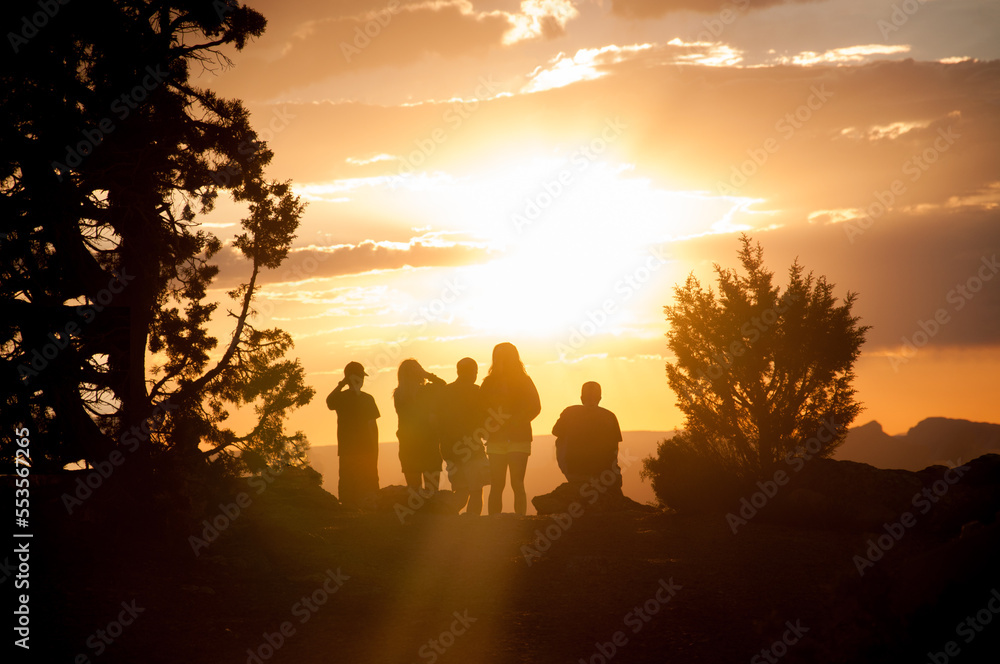 Familie sitzt am Rand des Grand Canyon und blickt in die tierstehende Sonne