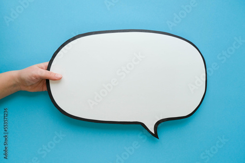Speech bubble in hand on a blue background. Comic cloud with a place for text