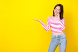 Photo portrait of nice young lady bite finger interested hold empty space dressed stylish striped look isolated on yellow color background