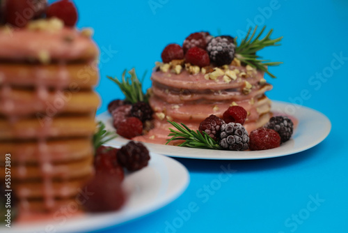 sweet delicious fragrant pink cupcakes in the shape of a heart and round with pink icing on top and decorated with blackberry raspberries and a sprig of rosemary on a blue background. for signage menu