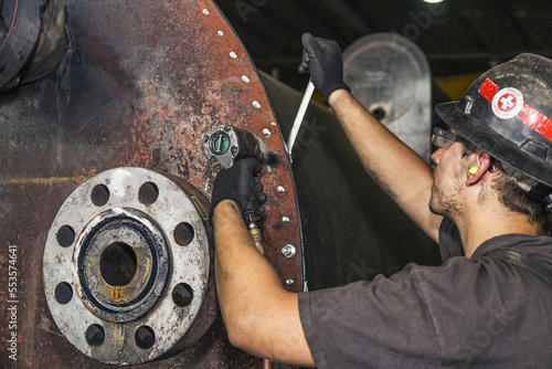 Bolting up the face plate of a line heater for pneumatic test, with the line heater coil installed into a line heater bath; Innisfail, Alberta, Canada